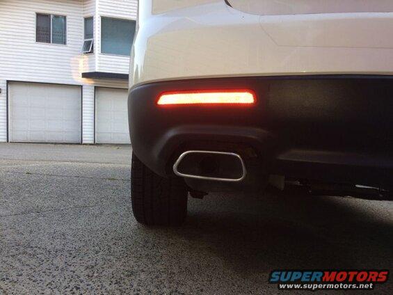 Rear view of a white SUV with a red LED reflector and exhaust pipe.