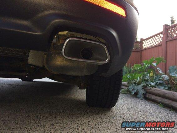 Close-up of a car's rear bumper and exhaust tip.