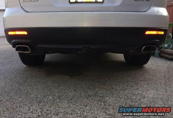 Rear view of a white Mazda CX-9 SUV with dual exhaust and trailer hitch.