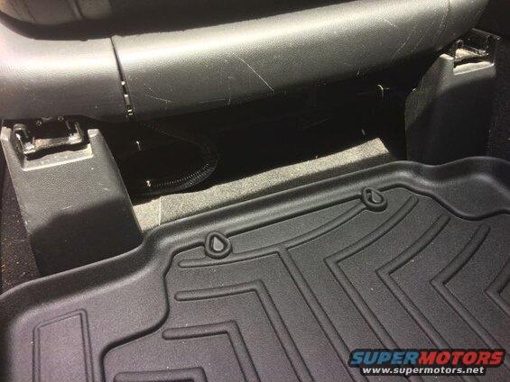 Black textured floor mat and underside of car seat with retention hook.