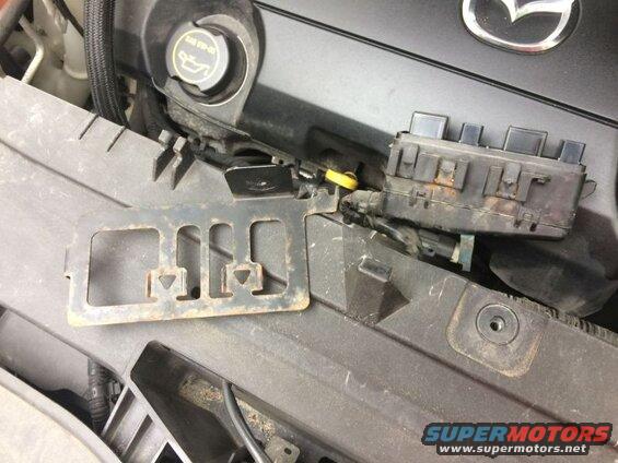 Mazda CX-9 engine bay with fuse box and metal bracket.