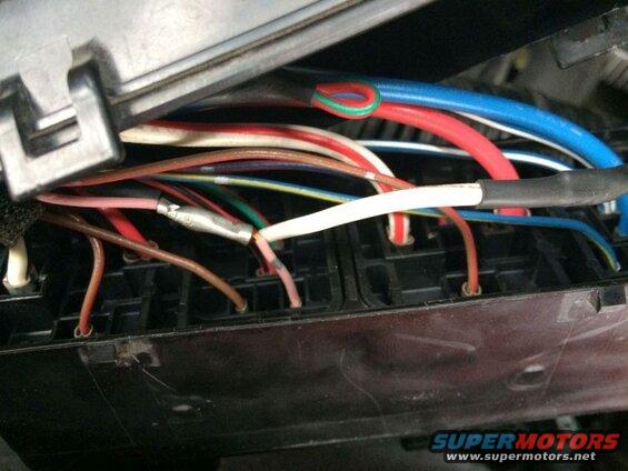 Close-up of a vehicle fuse box with many colorful wires.