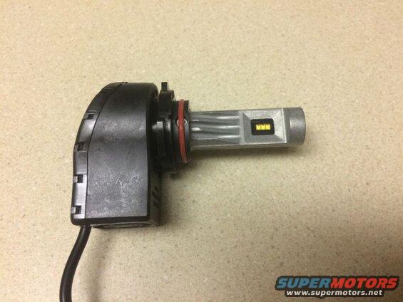 Silver and black LED headlight bulb with red O-ring on speckled countertop