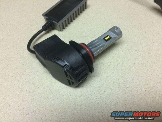 LED headlight bulb with black base and silver heat sink, connected to driver module.
