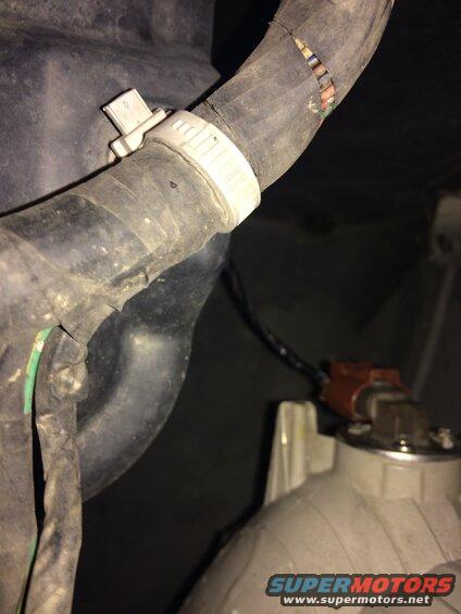 Damaged black rubber hose with exposed wires, secured by clamps, and a red electrical connector.