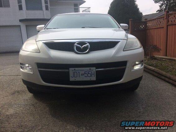White 2009 Mazda CX-9 front view with headlights on and BC license plate JD1 55H.