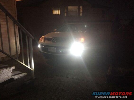 White 2009 Mazda CX-9 SUV parked at night with headlights on.