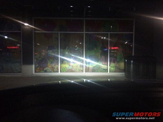Store window display with colorful candy and character graphics at night.