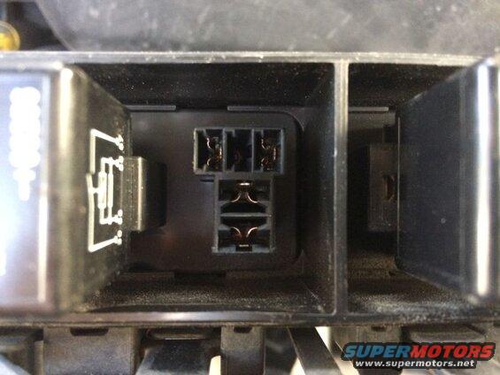Close-up of an open fuse box with empty slots and a relay.