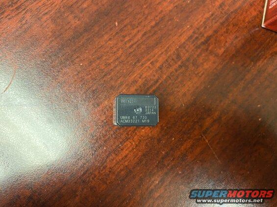 Black electronic component with text 'NMB', '80723 2314 JAPAN', 'UM46 67 730', 'ACM33221 M19'.