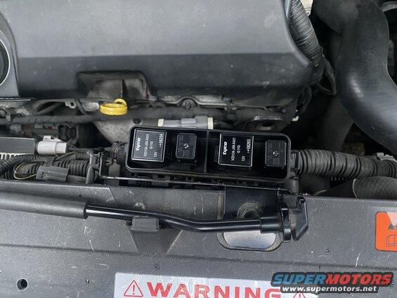Close-up of a 2009 Mazda CX-9 engine bay with a black relay box containing four Tyco relays.