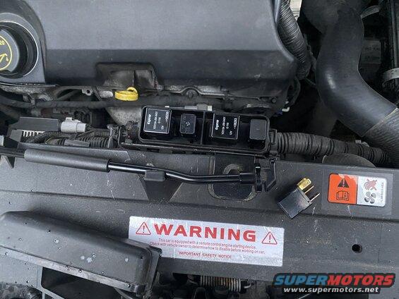 2009 Mazda CX-9 engine bay with fuse and relay box and a detached relay.