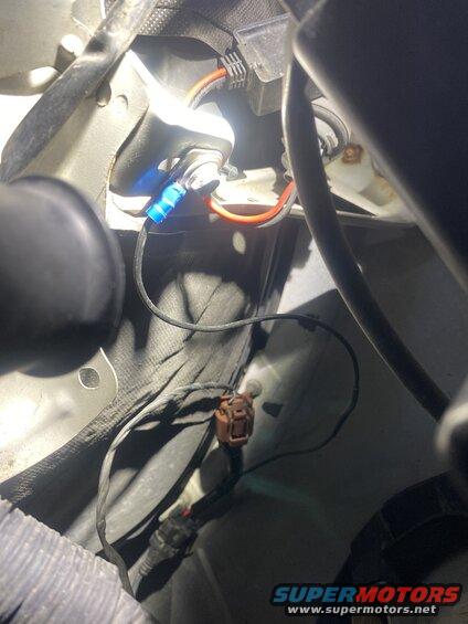 Close-up of blue LED light with red and black wires connected to a vehicle.