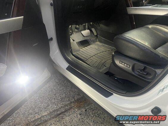 Interior of a white SUV showing driver's seat, floor mat, and Bose speaker.