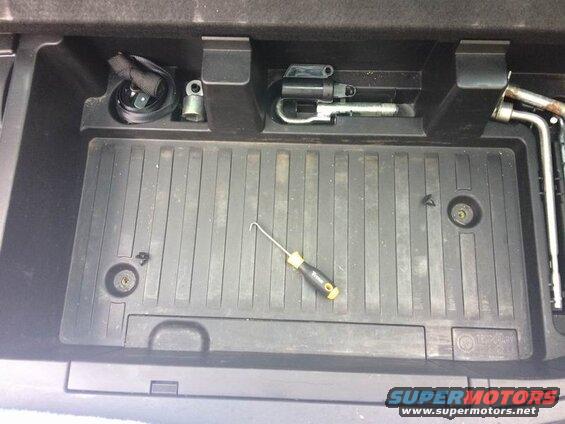Vehicle spare tire well with jack, lug wrench, and screwdriver.