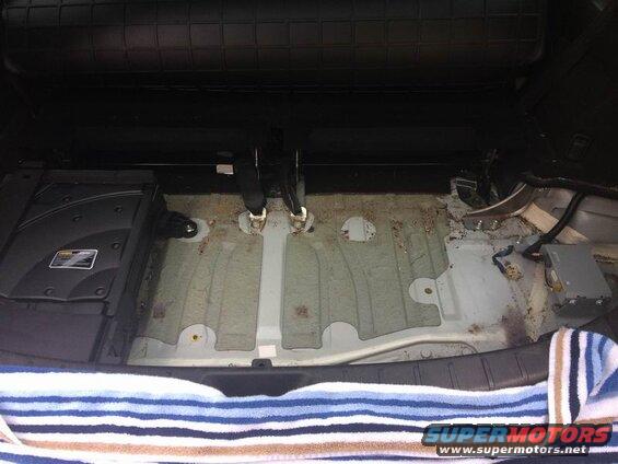 Interior of a vehicle cargo area with floor removed, showing undercarriage and components.