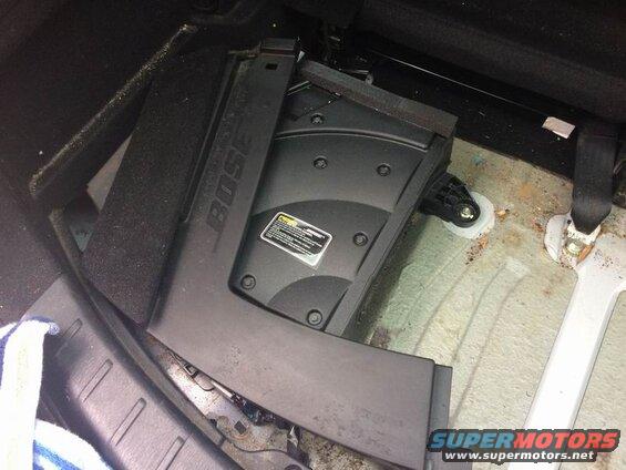 Black Bose subwoofer under rear seat of a vehicle.