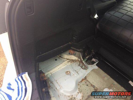 Interior cargo area of a vehicle, showing exposed floor pan and rear seats.
