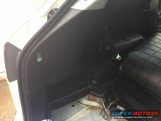 Interior cargo area of a white SUV, showing black trim, a seatbelt, and exposed floor.