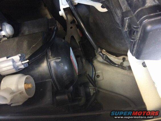 Left side: the low beam housing is right next to the fender. Twist off the weather cap, twist off the electrical connector, unclip the two bulb retainer arms (push in each arm so it can move outwards), pivot the retainer downwards and pull the bulb out.