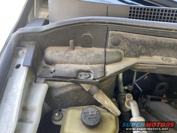 Engine bay of a 2009 Mazda CX-9 showing plastic cowling, hoses, and dust.