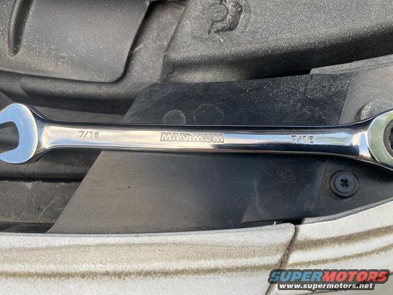 Chrome 7/16 inch ratcheting wrench on black plastic.