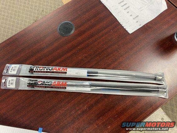 Two packages of StrongArm gas charged lift supports on a desk.