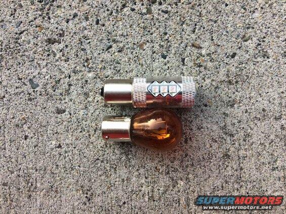 LED bulb and amber incandescent bulb on concrete