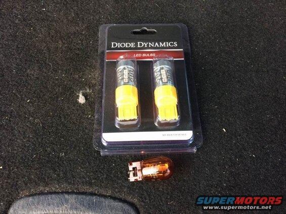 Diode Dynamics LED bulbs package next to an old amber bulb on carpet.