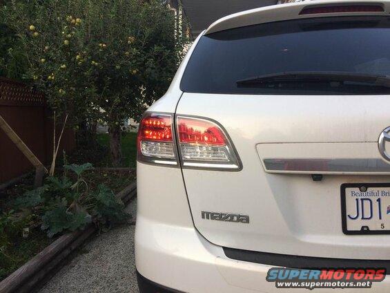 Rear passenger side of a white Mazda CX-9 SUV, showing taillight and license plate.