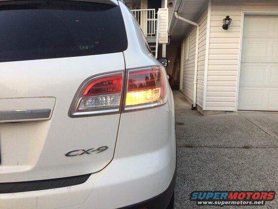 White 2009 Mazda CX-9 SUV, rear driver's side, brake light illuminated.