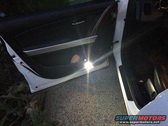 Interior of an open SUV door at night, light shining on the door panel and floor.
