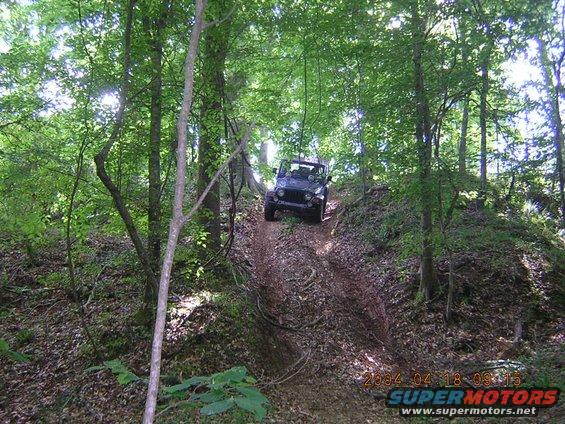 Dark SUV descending a muddy hill in a forest