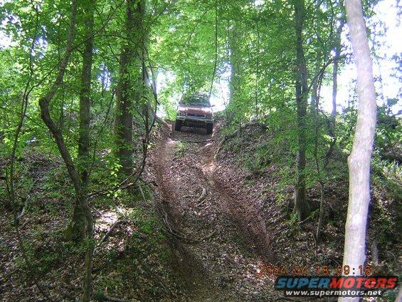 Red SUV climbing a muddy hill in a forest; timestamp 2004-04-18 09:16