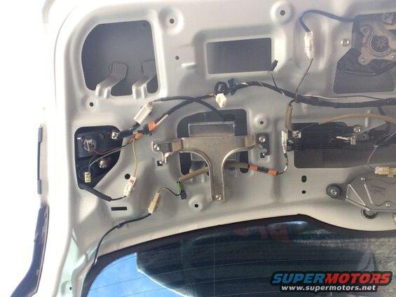 Interior of a car trunk showing wiring, taillight assembly, and motor.