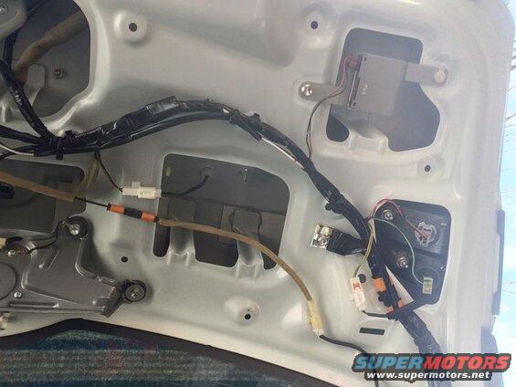 Underside of vehicle hood showing wiring harness, modules, and connectors.