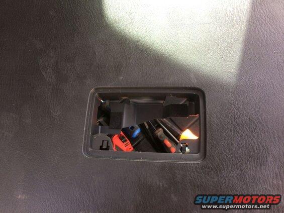 Black textured surface with a cutout showing red and blue electrical connectors.
