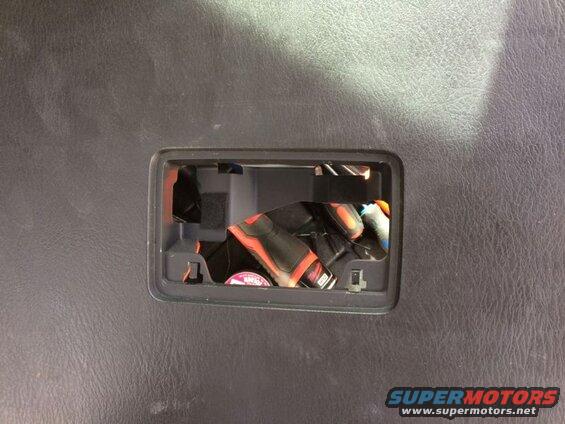 Close-up of a storage compartment with tools inside, set in a black textured surface.