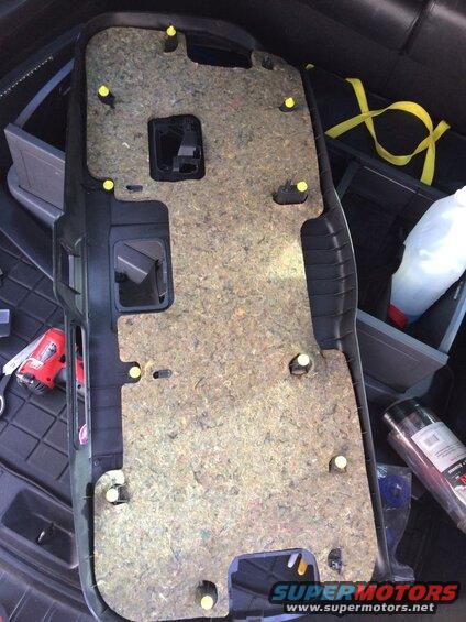 Removed car door panel with sound deadening material and yellow clips, red tool and spray can visible.