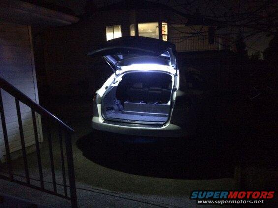 White SUV with open trunk and interior lights on at night.