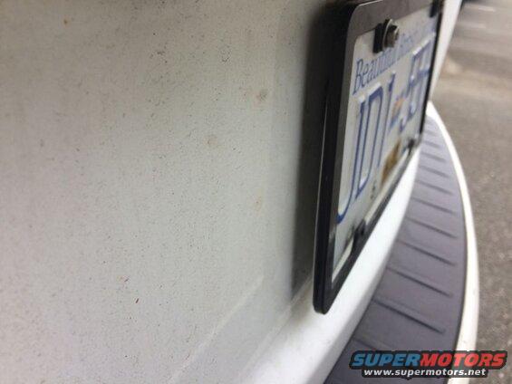 Close-up of a white vehicle's rear bumper and license plate