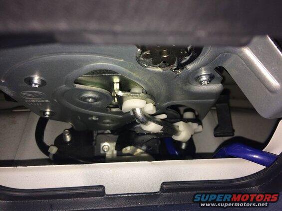 Close-up of car trunk latch mechanism with metal, white plastic, and black wires.