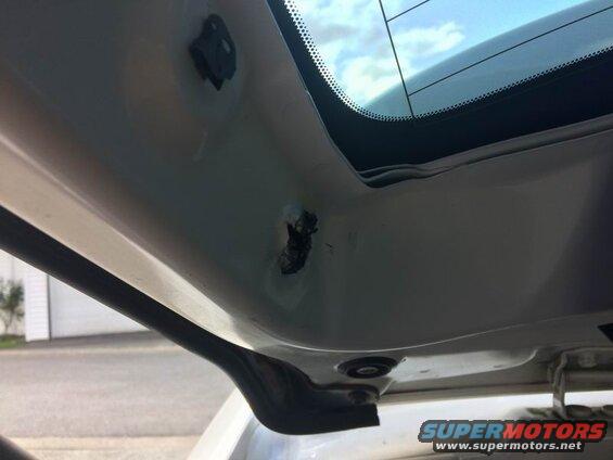 Interior of a white vehicle's rear hatch area with visible damage and trim mounting points.