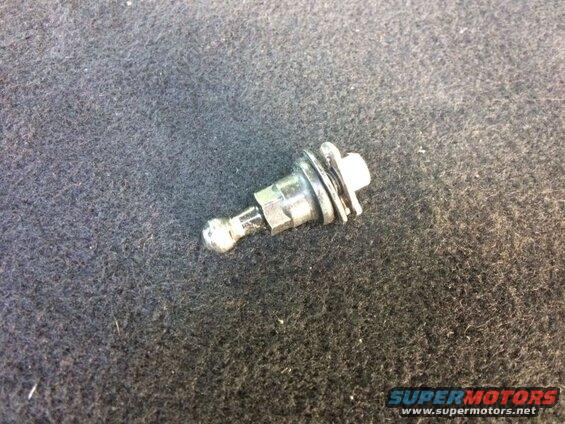 Small metal part with ball end and white plastic cap on dark textured surface