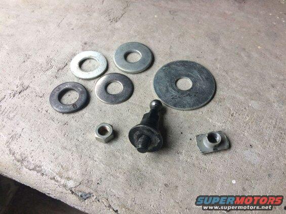 Assorted washers, nut, bolt with ball joint, and T-nut on concrete.