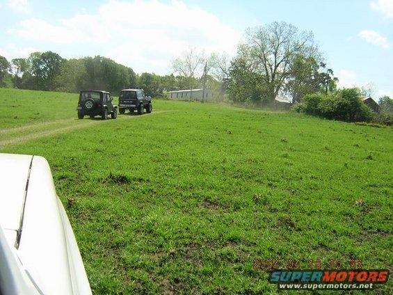 Two SUVs on a dirt road in a grassy field with buildings in the background. Date stamp reads 2004-04-18