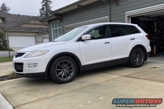White 2009 Mazda CX-9 SUV with dark gray wheels and window visors parked on a driveway.