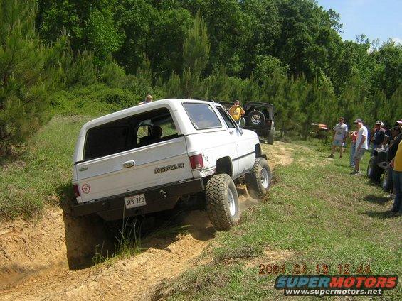White 1984 Chevrolet Blazer climbing a dirt hill with other vehicles and people watching