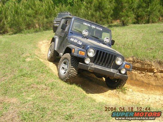 Blue Jeep Wrangler with "DELTA 4x4 CLUB" sticker on dirt trail, another SUV behind it