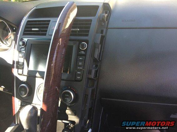 Disassembled car dashboard interior with infotainment screen, climate controls, and exposed mounting brackets.